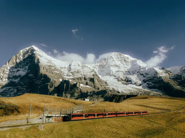 A red mountain railway below the snow-covered peaks of the Jungfrau region